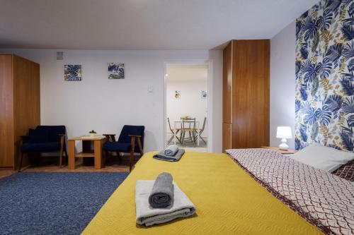 Un dormitorio con una cama amarilla con toallas. en Apartamenty przy Parku, en Łańcut