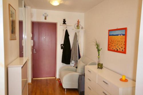 a living room with a white chair and a red door at Cozy flat with side Baltic Sea view in Pärnu
