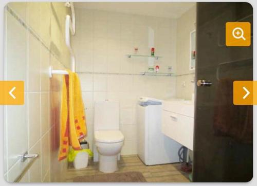 a white bathroom with a toilet and a sink at Cozy flat with side Baltic Sea view in Pärnu