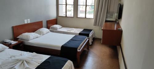 a room with two beds and a flat screen tv at Hotel La Rocca, Goiânia in Goiânia