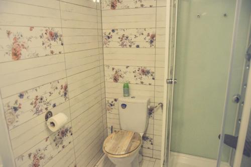 a bathroom with a toilet with flowers on the wall at Édes Otthon Vendégház in Nagybörzsöny