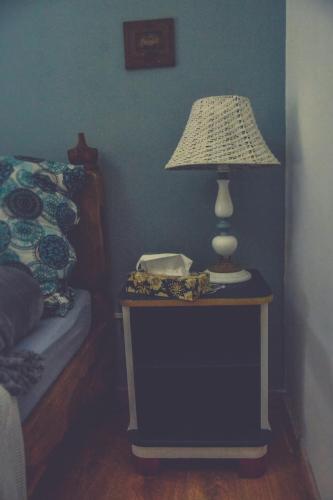 a table with a lamp on it next to a bed at Édes Otthon Vendégház in Nagybörzsöny