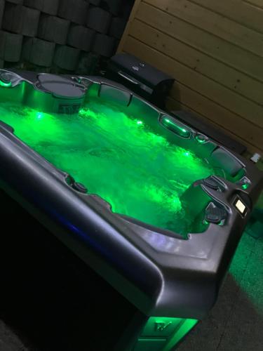 a hot tub with green lighting in a room at Bé-La 2 Vendégház in Szomolya