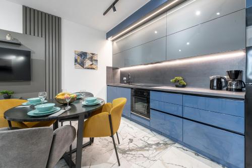 a kitchen with blue cabinets and a table and chairs at Sunset Premium Residence II & III in Dubrovnik