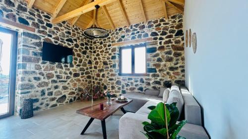 een woonkamer met stenen muren en een bank en een tafel bij Cassiopea Guest House Evia Greece in Nerotriviá
