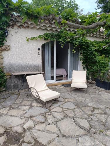 2 chaises blanches assises sur une terrasse en pierre dans l'établissement B&B Chambre indépendante double, à Deaux