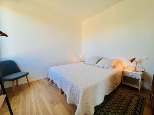 ein Schlafzimmer mit einem weißen Bett und einem blauen Stuhl in der Unterkunft Villa Quiberon, 2 pièces, 2 personnes - FR-1-478-285 in Quiberon
