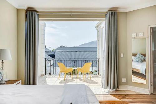 1 Schlafzimmer mit einem Tisch und 2 gelben Stühlen in der Unterkunft 2 Villefranche, Franschhoek in Franschhoek