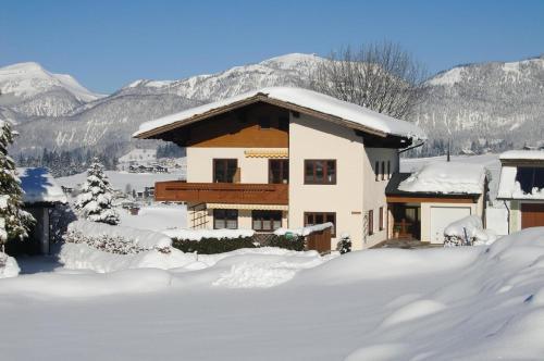 een huis bedekt met sneeuw met bergen op de achtergrond bij Gemütliches Appartement in Abtenau mit Garten und Terrasse in Abtenau