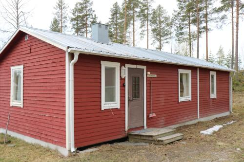 a red house with a door in a field at Trehörningsjö camping & stugor in Norrfors