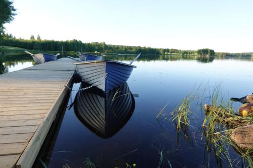 two boats are docked at a dock on a lake at Trehörningsjö camping & stugor in Norrfors