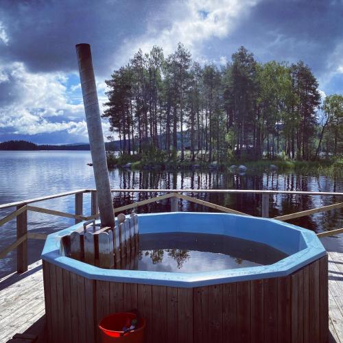 a bath tub sitting on a dock next to a body of water at Trehörningsjö camping & stugor in Norrfors