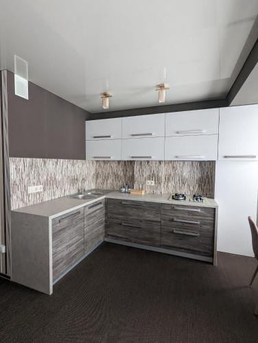 eine Küche mit weißen Schränken und einer Arbeitsplatte in der Unterkunft CosHOME - apartament in Chişinău