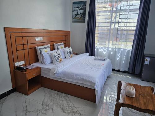 een slaapkamer met een groot bed met een houten hoofdeinde bij ELITE PEAK LUXURY LODGE in Dodoma