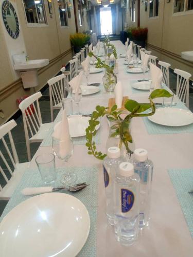 a long table with white plates and glasses and candles at ELITE PEAK LUXURY LODGE in Dodoma