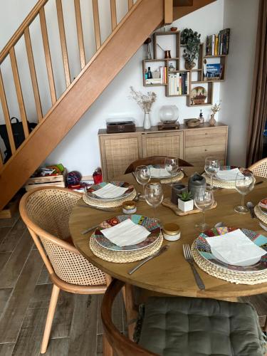 une table en bois avec des chaises et un escalier en bois dans l'établissement Elegant Bohemian Olympics Apartment - Near Paris, à Alfortville