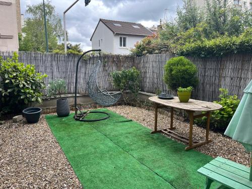 un jardin avec une table et de l'herbe verte dans l'établissement Elegant Bohemian Olympics Apartment - Near Paris, à Alfortville