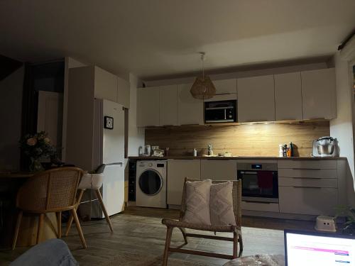 une cuisine avec des armoires blanches et une table et des chaises dans l'établissement Elegant Bohemian Olympics Apartment - Near Paris, à Alfortville