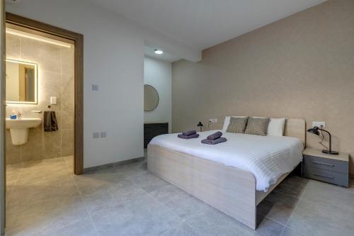 a bedroom with a large white bed and a sink at Urban Oasis 3BR Duplex in a Prime Location in San Ġwann