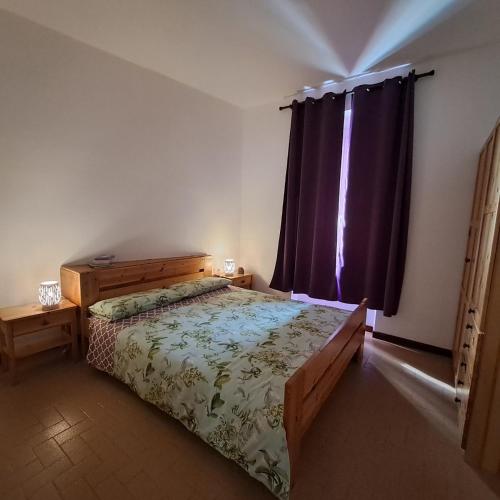 a bedroom with a bed and a window with purple curtains at Da Vinci Refuge 2 in Limonta