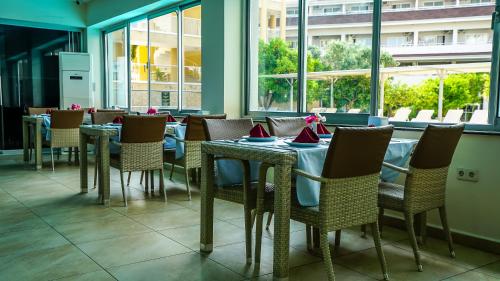 a dining room with tables and chairs and windows at Catty Cats Garden Hotel in Side