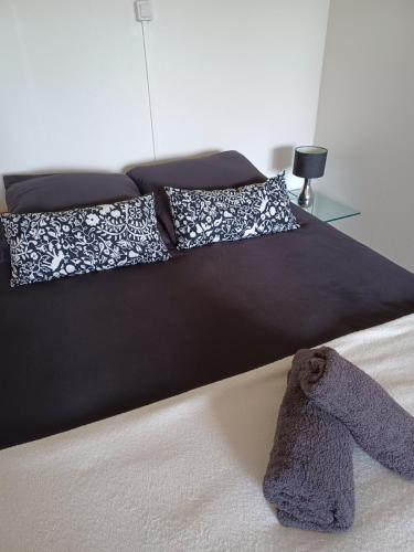 Una cama con edredón negro y almohadas. en Charmant studio avec parking fermé proximité autoroute en Mulhouse