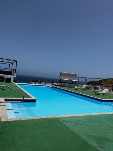 een groot zwembad met blauw water en groen gras bij The View Hotel in Tongon