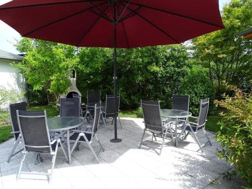 een tafel en stoelen met een rode parasol bij Große Ferienwohnung in Pudagla mit Garten, Terrasse und Grill in Pudagla