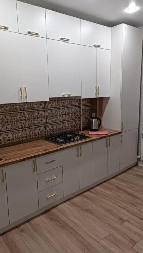 uma cozinha com armários brancos e uma bancada em Батыс em Aqtöbe