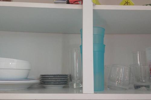 a shelf with bowls and other glass items on it at Quiet and cozy cunuco guesthouse in Savaneta in Savaneta