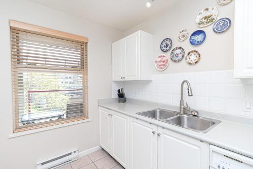 a white kitchen with a sink and plates on the wall at Harbour Retreat in Victoria