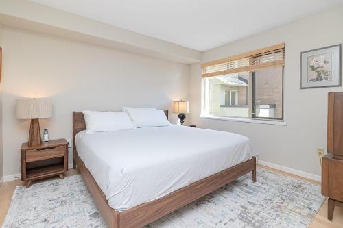 a white bedroom with a bed and a window at Harbour Retreat in Victoria