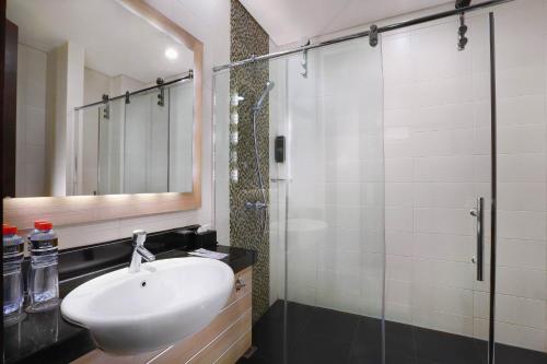 een badkamer met een wastafel en een glazen douche bij Hotel Neo Gubeng by ASTON in Surabaya
