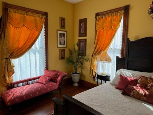 a bedroom with a bed and a couch and windows at Woodbine Inn and Restaurant in Madisonville