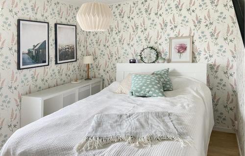 a bedroom with a white bed with pink floral wallpaper at Stunning Home In Gotland With Kitchen in Gnisvärd