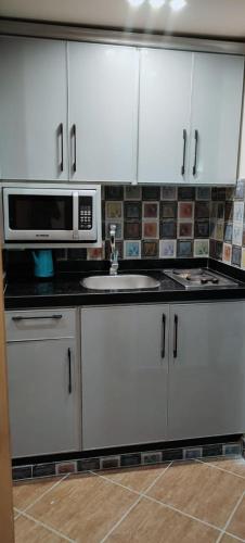 a kitchen with white cabinets and a microwave and a sink at Palmera El Sokhna Chalets Families Only in Ain Sokhna