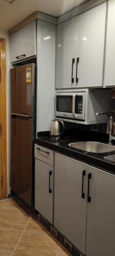 a kitchen with white cabinets and a stainless steel refrigerator at Palmera El Sokhna Chalets Families Only in Ain Sokhna