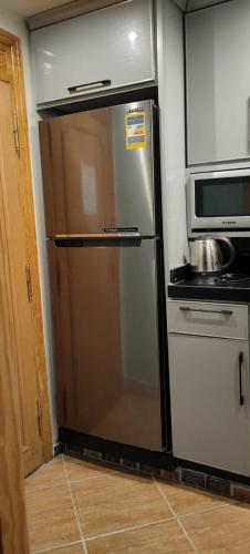 a stainless steel refrigerator in a kitchen with a microwave at Palmera El Sokhna Chalets Families Only in Ain Sokhna