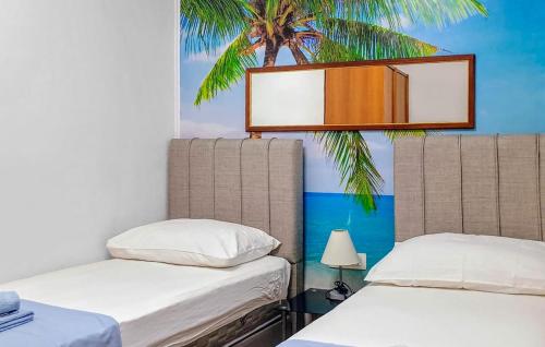 two beds in a room with a palm tree on the wall at Nice Apartment In Mimice With Outdoor Swimming Pool in Mimice