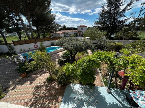 une piscine dans un jardin planté d'arbres et de plantes dans l'établissement Maison invitant aux voyages 20mn de la plage, à Béziers