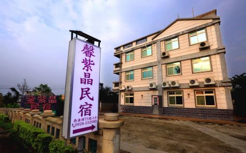 un edificio con una señal delante de él en 金門馨紫晶民宿, en Jinning