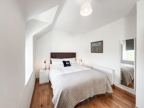 a white bedroom with a bed and a window at The Old Cheese Loft in Colfin