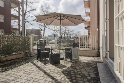 Una mesa y sillas con una sombrilla en una acera en Maggie House, en Piacenza