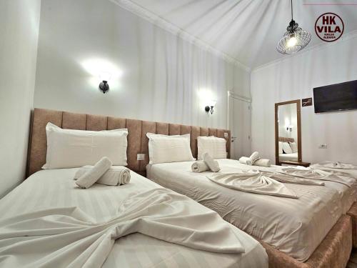a bedroom with two beds with white sheets and a mirror at Vila HK in Krujë