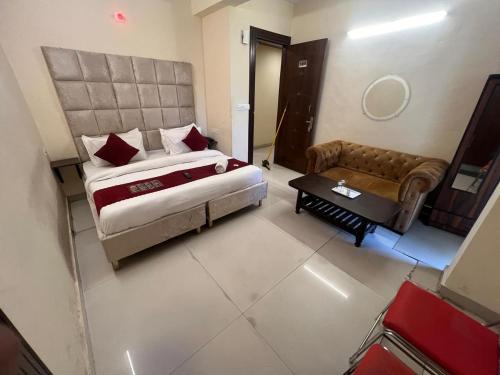 sypialnia z dużym łóżkiem i kanapą w obiekcie Hotel Kaushambi Grand w mieście Ghaziabad