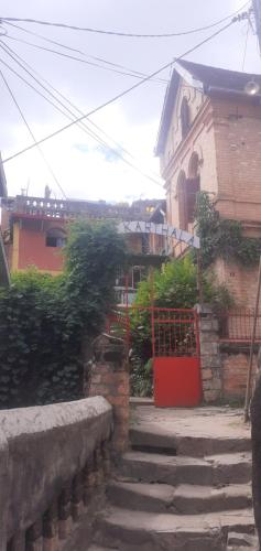 a brick house with a red gate and a stairway at Le Karthala Chambres D'Hotes in Antananarivo