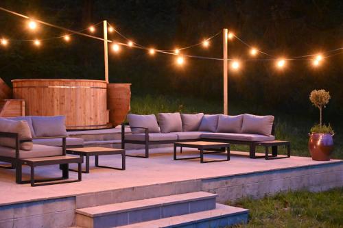eine Terrasse mit Sofas, Tischen und Lampen in der Unterkunft Private Oasis: Luxe 20-guest Estate, Jacuzzi, 8 Ha in Bazeilles