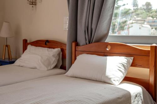 sypialnia z 2 łóżkami i oknem z zasłonami w obiekcie Nefeli Rooms w mieście Agia Marina Nea Kydonias