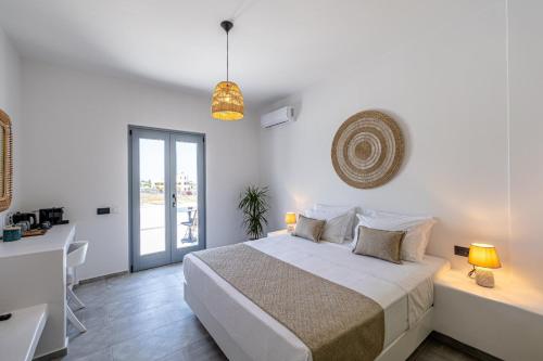 a white bedroom with a bed and a desk at Bonsai Luxury Suites in Karterados