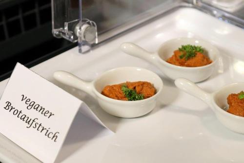 three bowls of food on a sink with a sign at Hotel Märkischer Hof in Luckenwalde